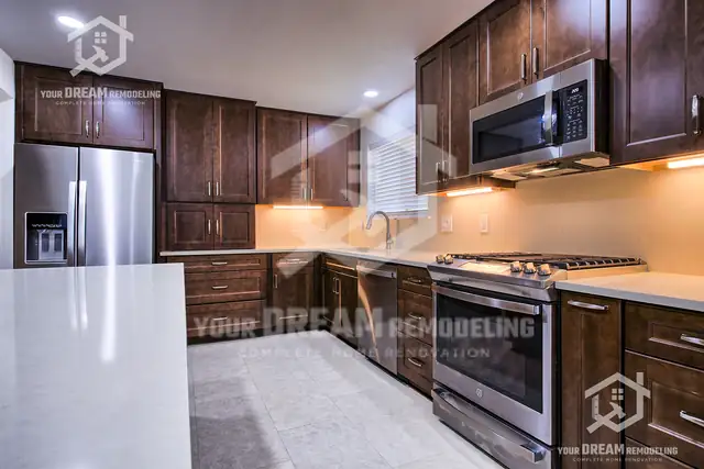 Cherry kitchen cabinets with under-cabinet lighting over a stainless range and white quartz counters