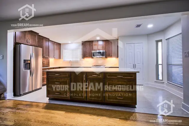 Kitchen with stained shaker cabinets, a large island with a light quartz top, stainless appliances and wood floors