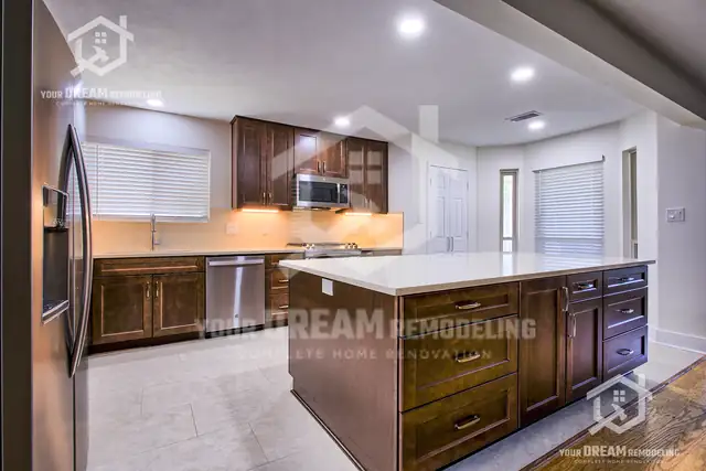 Kitchen with cherry-stained shaker cabinets, white quartz island and stainless appliances