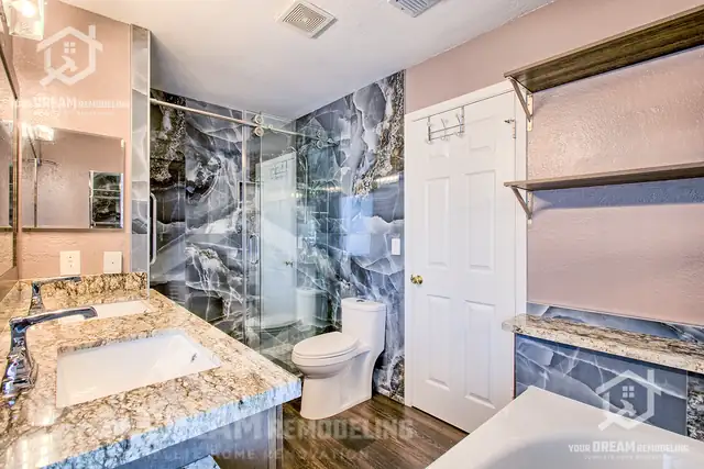 Bathroom by Your Dream Remodeling with a granite vanity top, a glass shower in dark blue marble-look tile and a matching tub surround
