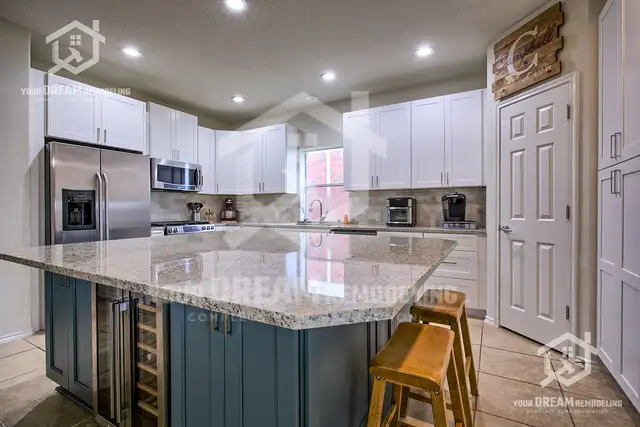 Kitchen with white shaker cabinets, a slate-blue island with wine fridge and granite counters