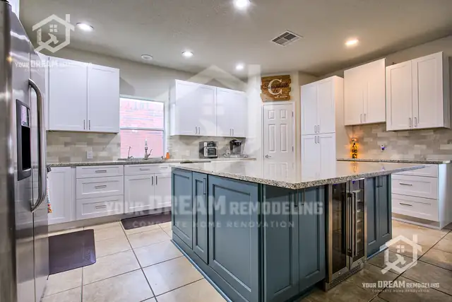 Kitchen with white shaker cabinets, a slate blue island with a wine fridge, granite counters and a tile floor