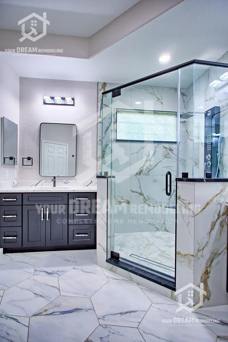 Bathroom remodeling Houston project with a frameless glass walk-in shower, marble-look porcelain tile, charcoal vanity and stone-look floor